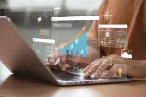 Person working on a laptop with virtual data analytics dashboards and digital marketing icons projected on the screen, including graphs, charts, email, SEO, and video elements.